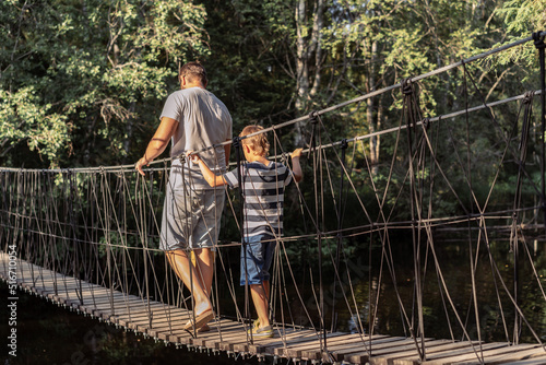 father and child walking over rope bridge in the forest. Ruskeala waterfall in Karelia, Russia. Active life concept. Image with selective focus