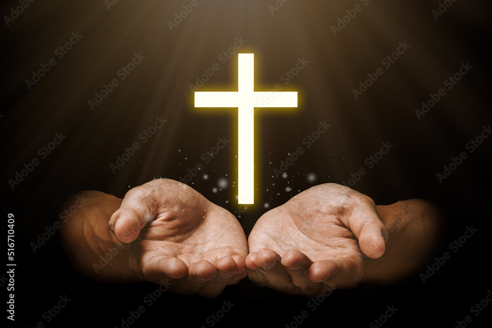 Praying hand with jesus christ and shadows reaching out against a dark