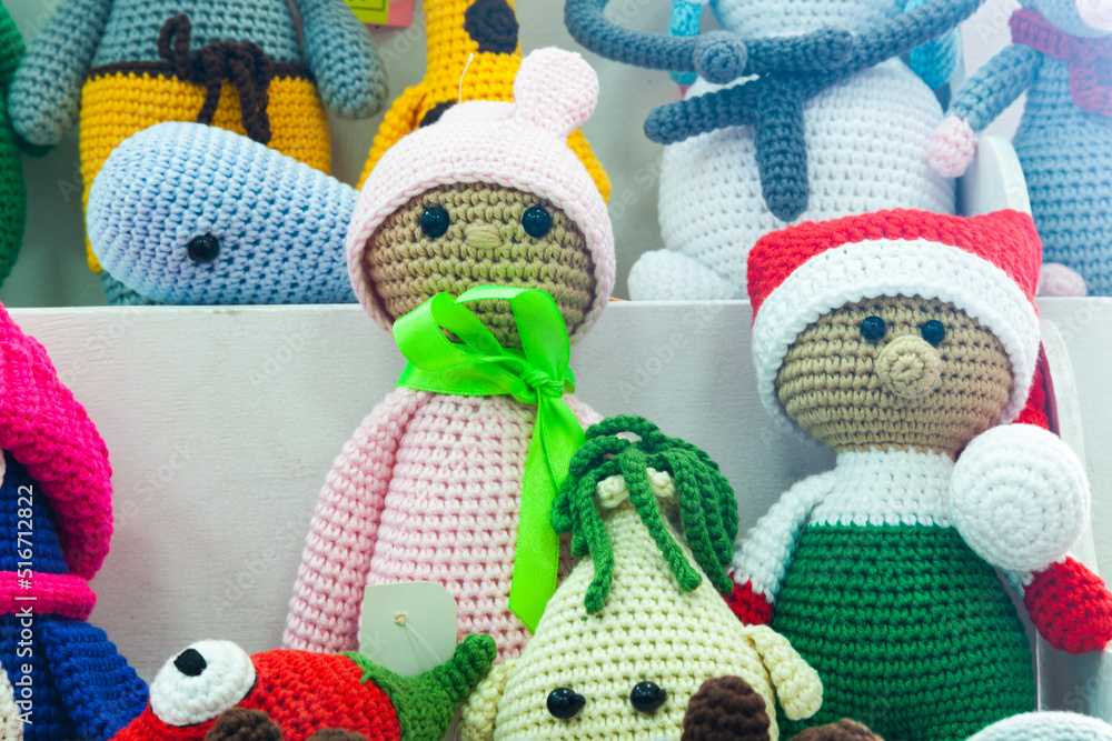 Multi-colored handmade knitted dolls standing on the shelves, close-up.