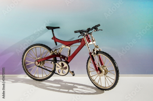 Realistic model of a toy metal full-suspension mountain bike. Miniature bicycle on a colored background with text space.
