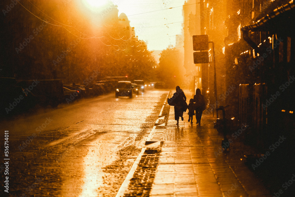 Rainfall, storm in the city. Puddles, people in the rain, sunset. Defocused