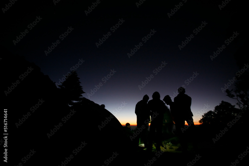 Hikers or tourists stands on mountain top at sunset