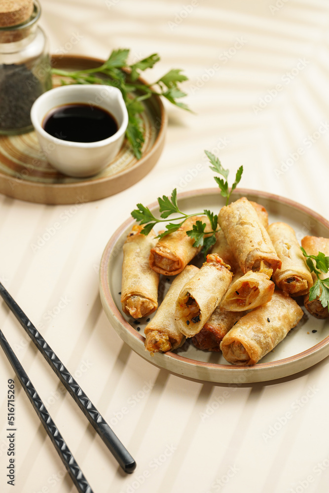 Traditional southeast asian starter dish spring or summer rolls - deep fried dim sum dumplings stuffed with vegetables with soy sauce, fresh coriander on grey plate with black chop sticks Traditional southeast asian starter dish spring or summer rolls - deep fried dim sum dumplings stuffed with vegetables with soy sauce, fresh coriander on grey plate with black chop sticks