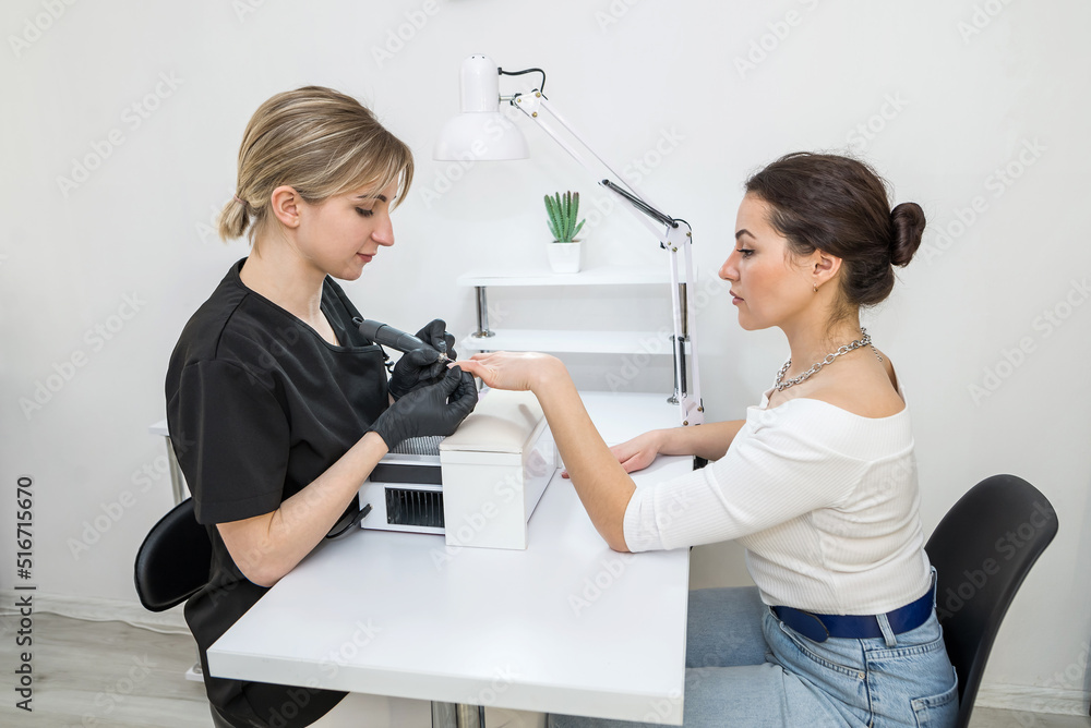 Professional hardware manicure on an electric machine in a nail salon. The process of lifting the cuticle with a cutter. Professional hardware manicure on an electric machine in a nail salon. The process of lifting the cuticle with a cutter.
