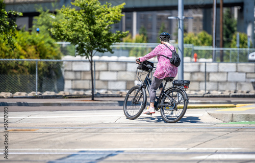 Fototapeta Naklejka Na Ścianę i Meble -  Woman with a backpack takes care of her health and exercises cycling while riding on a bike path