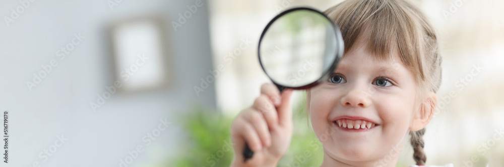 Pretty little child hold magnifying glass and explore world through it