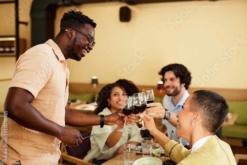 A group of multicultural friends is celebrating an event and reunion in a restaurant and toasting with wine.
