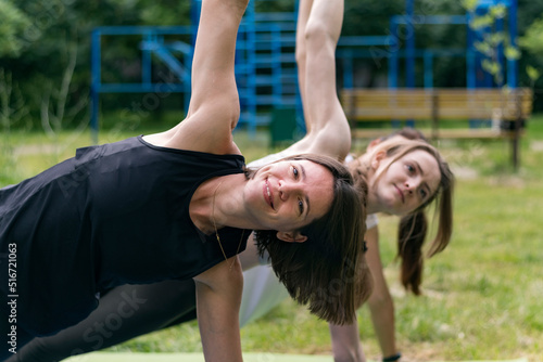 Group fitness classes. Athletic young women make a side bar. Girls play sports in the park.