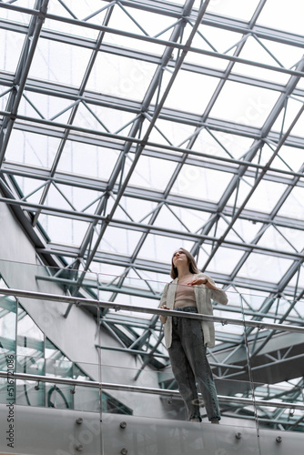 Young woman walks around the futuristic building. Girl in modern building. High-tech style.