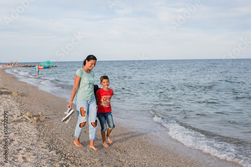 boy and mother walking along the sea beach