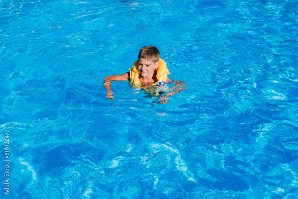 boy in an inflatable jacket in the pool in summer