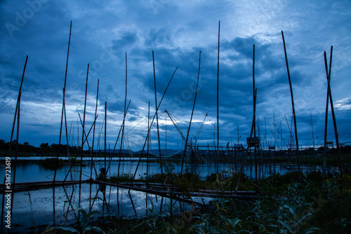Traditional fishing tool or bamboo fish trap on sunset light, landscape silhouette. © peterkai