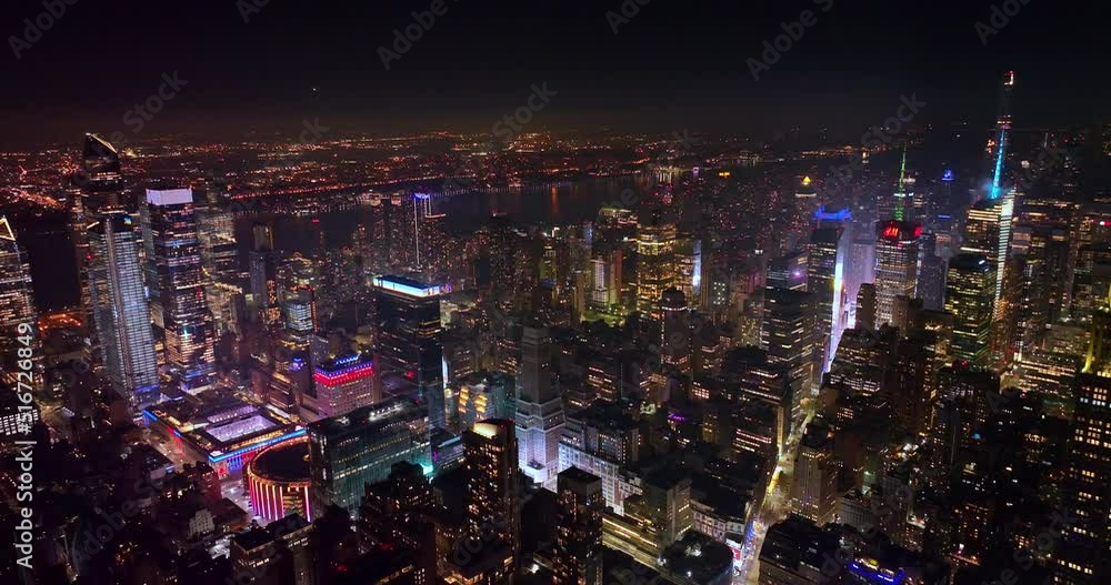 Immense New York panorama at night time. Tremendous city scenery in lights with dark river crossing the city. Top view.