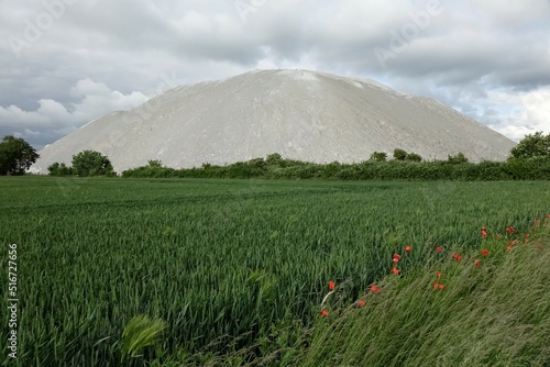 Potash mountain Wetterberg (Kalimandscharo) with green grain field in the foreground under a cloudy spring sky (horizontal), Giesen, Lower Saxony, Germany photo