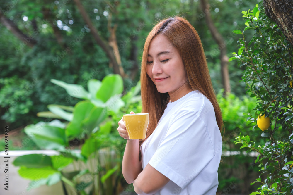 Portrait image of a beautiful young asian woman holding and drinking hot coffee in the outdoors Portrait image of a beautiful young asian woman holding and drinking hot coffee in the outdoors