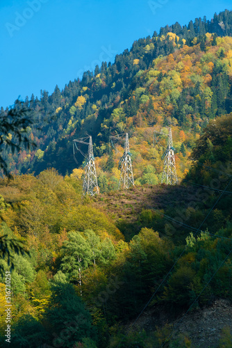 Picturesque autumn landscape  power line support in a mountainous area on a sunny day. High-voltage power transmission lines in the mountains. Vertical photo