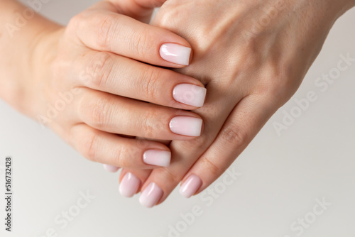 Female hands with beautiful nails with stylish trendy nude manicure.