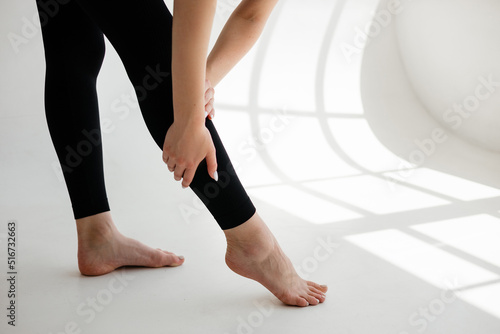 Girl in black leggings holding her leg
