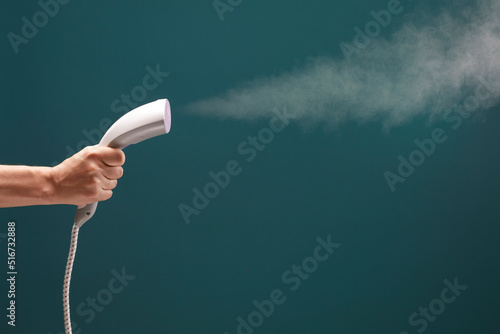 Fototapeta Close up view of male hand with vertical steamer isolated on green background