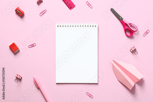 Blank paper notepad with school supplies on pink table. Flat lay, top view, copy space.