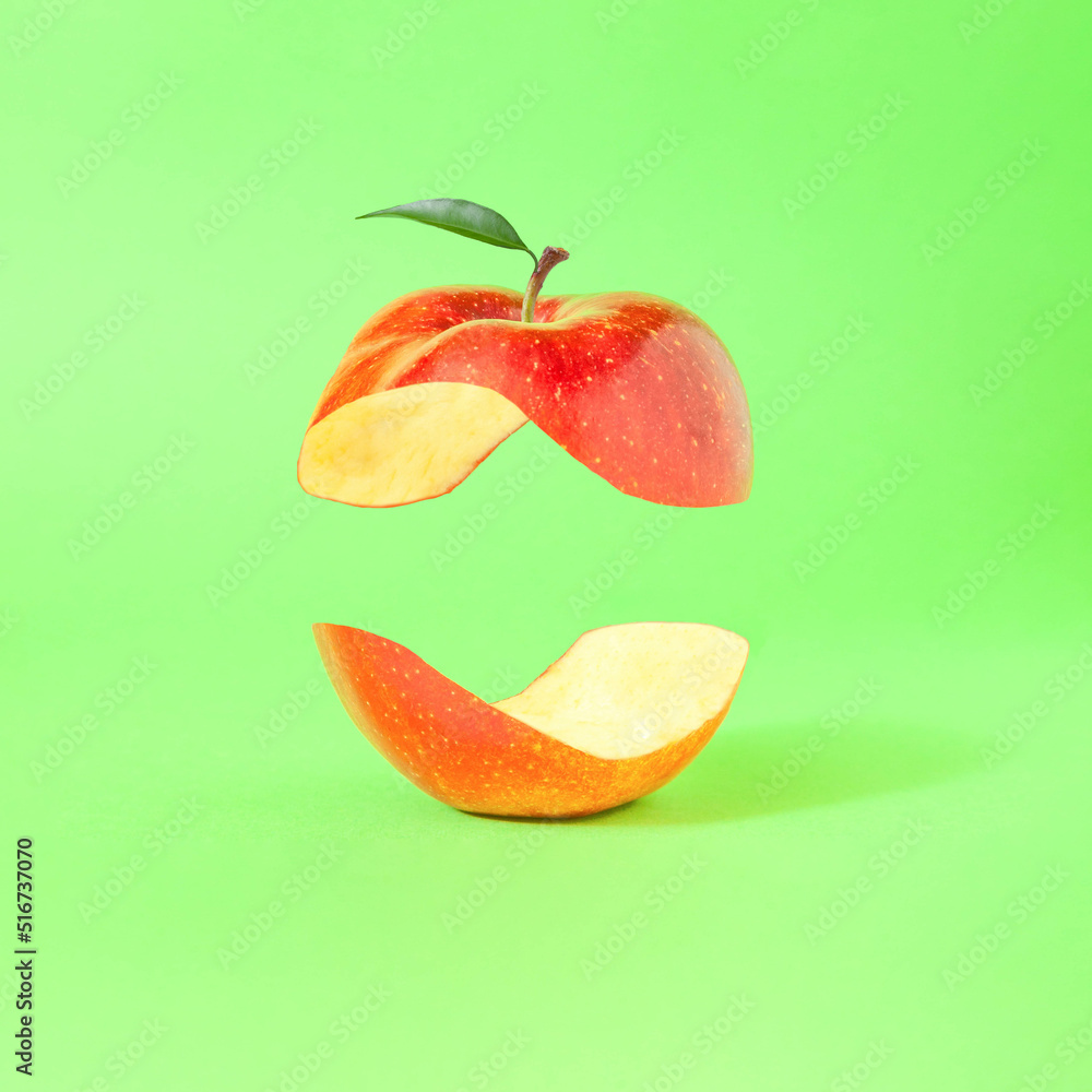 Minimal composition with levitating halved red apple against bright green background. Jin and jang concept. Balanced healthy diet idea. - obrazy, fototapety, plakaty 