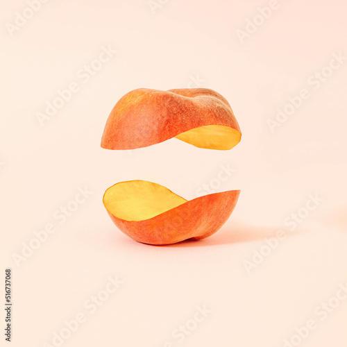 Creative composition with levitating halved peach against pastel powder background. Jin and jang concept. Balanced vegan diet idea.