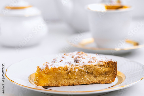 Piece of delicious homemade pie on white plate  cup and teapot