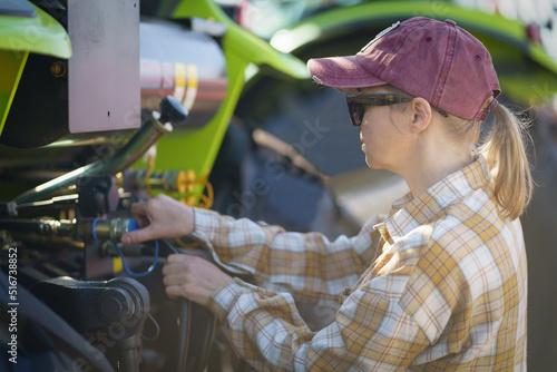 Female farmer trying to repair tractor in field. © PAstudio