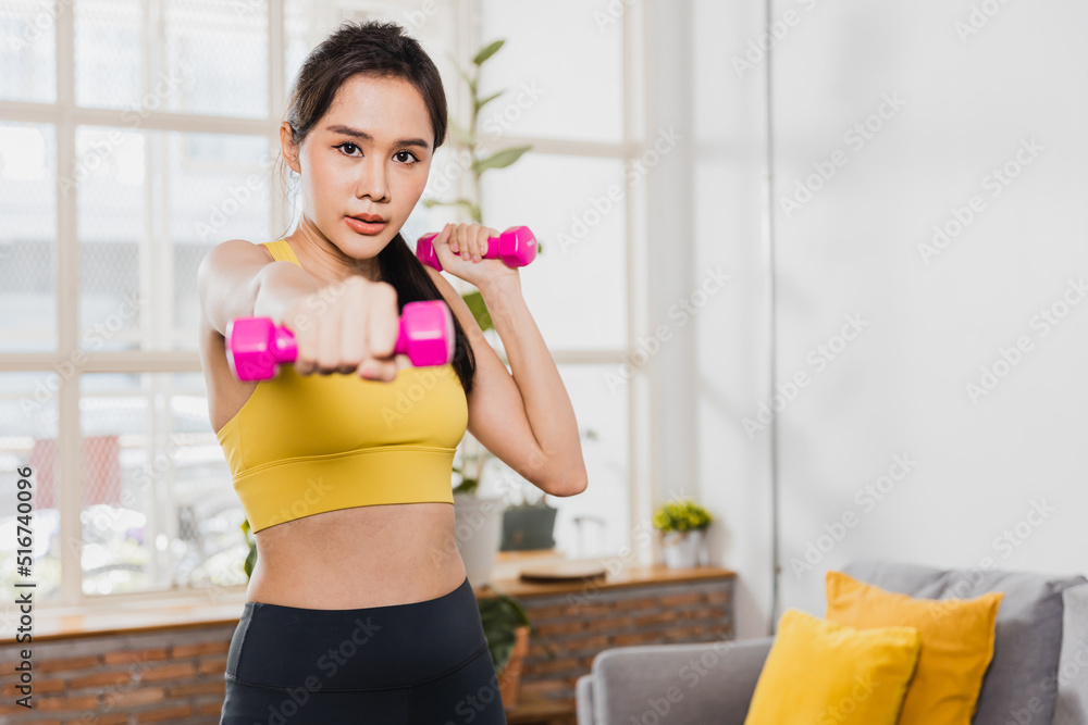Asian beautiful woman in sport wear exercise and work out at home with dumbbells Asian beautiful woman in sport wear exercise and work out at home with dumbbells