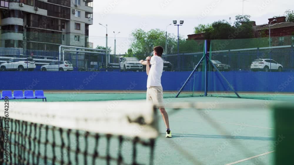 4K. A young man is warming up on the tennis court. 4K. A young man is warming up on the tennis court.