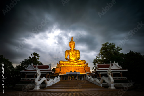 Beautiful Big Golden Buddha statue against night sky in Thailand temple,khueang nai District, Ubon Ratchathani province, Thailand.Amazing Buddha image with evening dark sky clouds with movement.