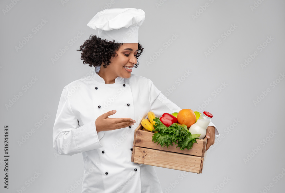 cooking, culinary and people concept - happy smiling female chef in toque holding food in wooden box over grey background cooking, culinary and people concept - happy smiling female chef in toque holding food in wooden box over grey background