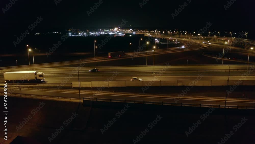 Drone shot on night freeway with crossroads and bridges, low flight close to highway with car traffic. Aerial view of overpasses and roads, bridges, traffic in the suburbs of Warsaw at night Drone shot on night freeway with crossroads and bridges, low flight close to highway with car traffic. Aerial view of overpasses and roads, bridges, traffic in the suburbs of Warsaw at night