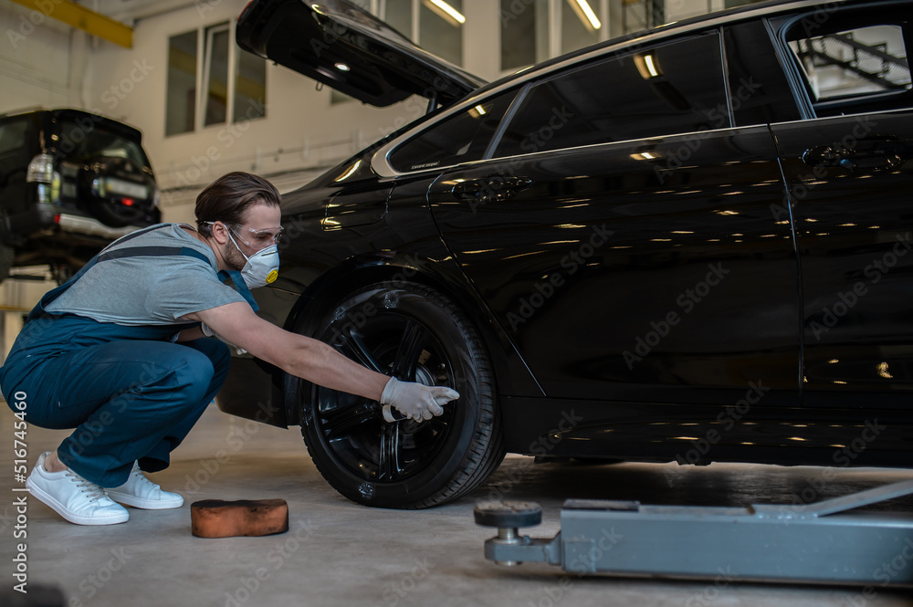 Service station worker coating the car tire with black gloss Service station worker coating the car tire with black gloss