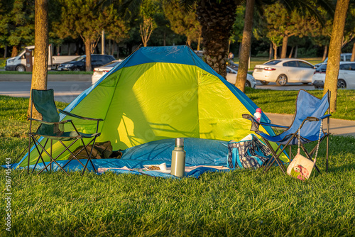 Camping tent with desk and chairs in a park.Camping equipments.
