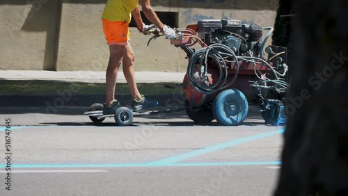 Painting road lanes. Road works. A worker is painting the machine blue lanes.