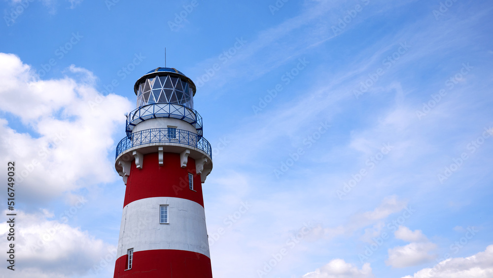 Lighthouse against the background of the blue sky. Lighthouse on a clear sunny day