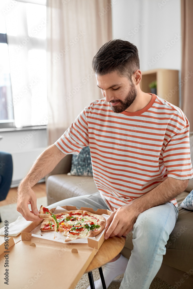 food delivery, consumption and people concept - happy man opening box and eating takeaway pizza at home food delivery, consumption and people concept - happy man opening box and eating takeaway pizza at home