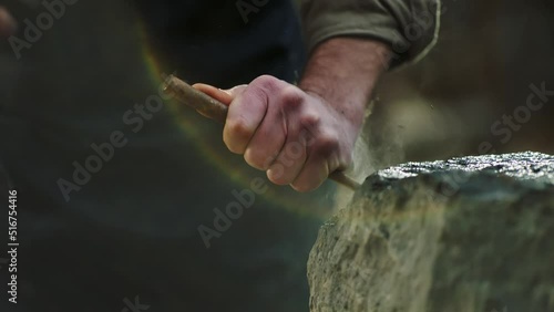 Sculptor shaping a big stone. Rock breaking