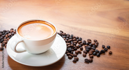 Close-up of a cup of latte with golden foam and mixed or blend coffee beans on an old wooden floor, top view.