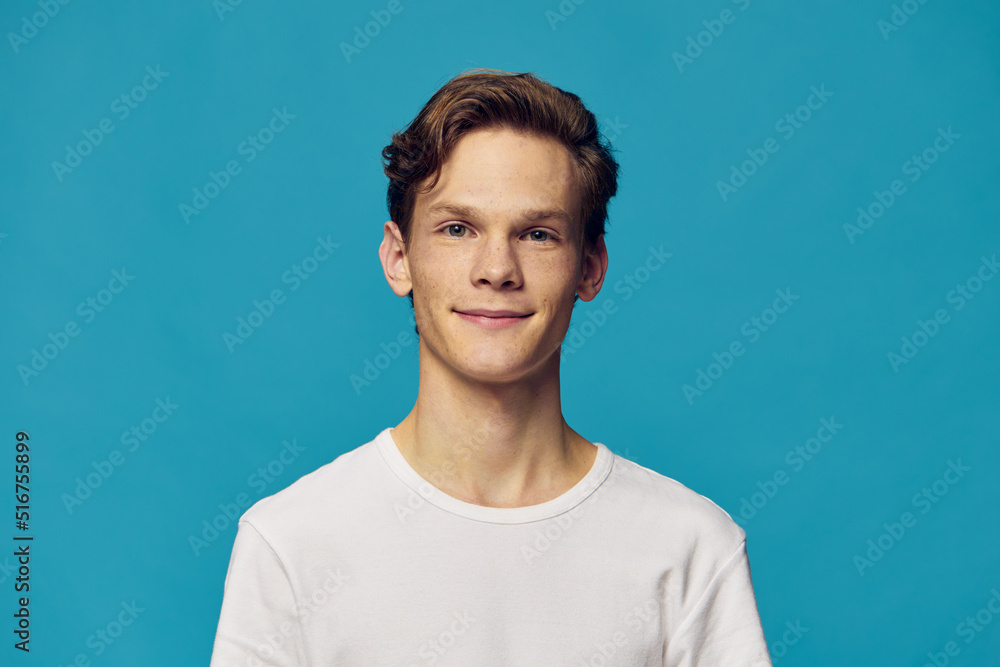 portrait of a handsome, cute guy in a white t-shirt on a blue background portrait of a handsome, cute guy in a white t-shirt on a blue background