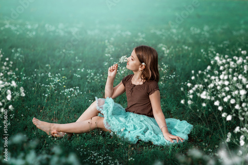 Fototapet A 10-year-old girl walks in a field with white flowers