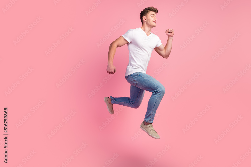 Brunette man in sneakers denim outfit running in air hurrying for discounts for advertising studio shot isolated on pink background