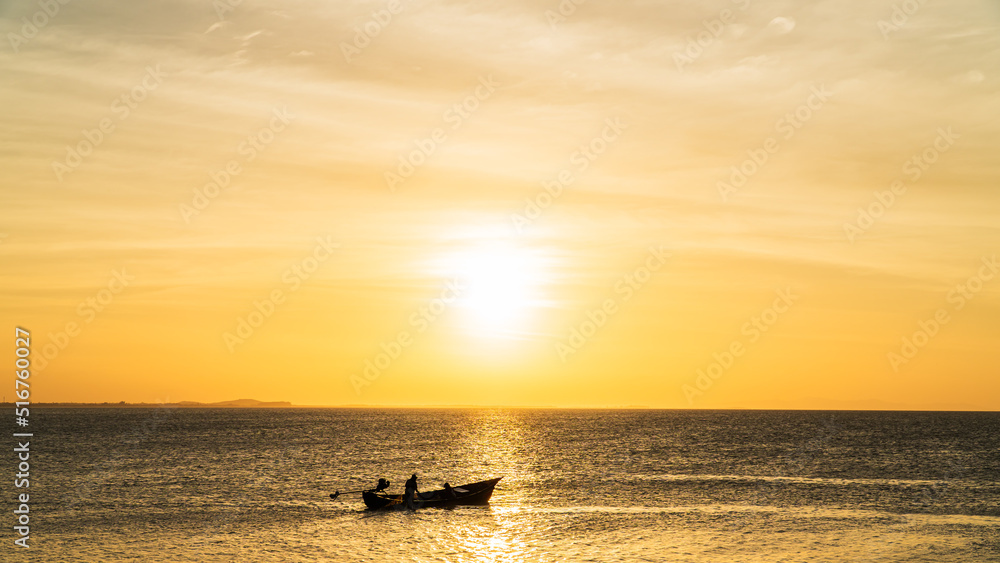 Sunset sky clouds over sea in the evening with orange sunlight and traditional fishing boat 