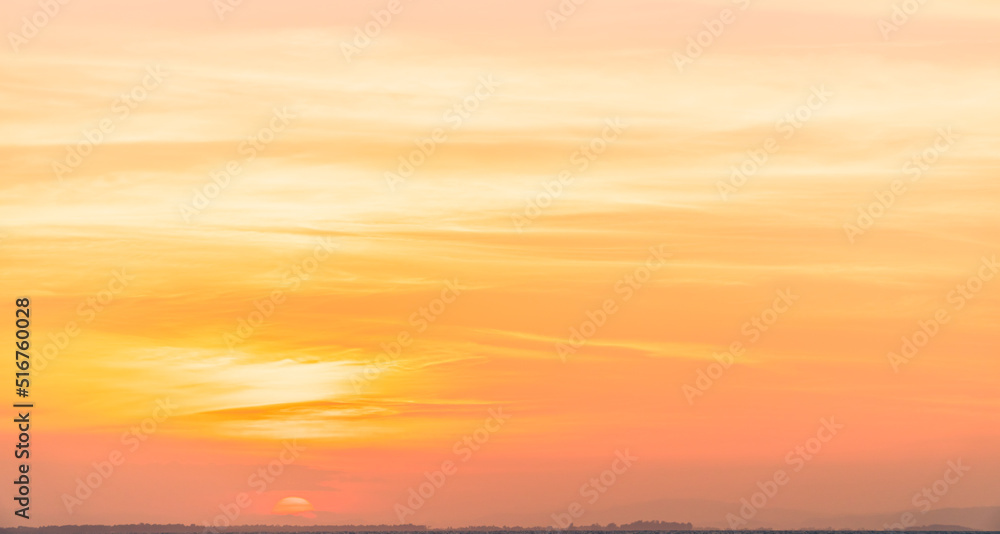Sunset sky clouds in the evening with orange sunlight in golden hour natural background 