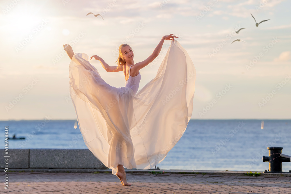 A dancing ballerina in a white flying skirt and tights on the ocean embankment or on the sea beach, surrounded by seagulls in the sky. A dancing ballerina in a white flying skirt and tights on the ocean embankment or on the sea beach, surrounded by seagulls in the sky.