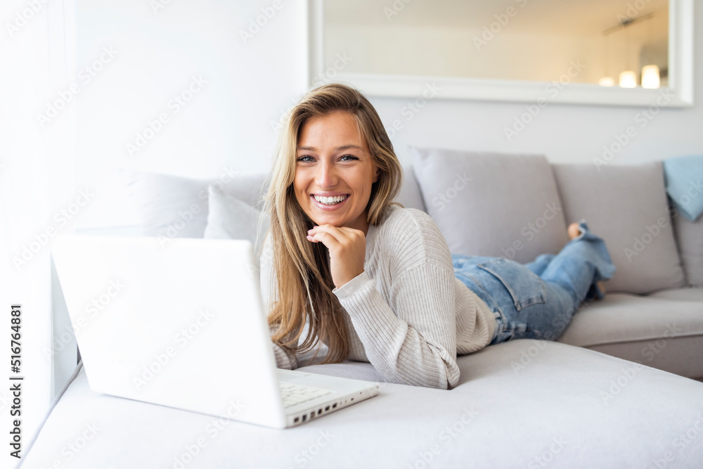 Beautiful Young Woman relaxing and surfing the net at home. A young woman is using a laptop comfortably in the living room at home. Woman at home working on a computer. Beautiful Young Woman relaxing and surfing the net at home. A young woman is using a laptop comfortably in the living room at home. Woman at home working on a computer.