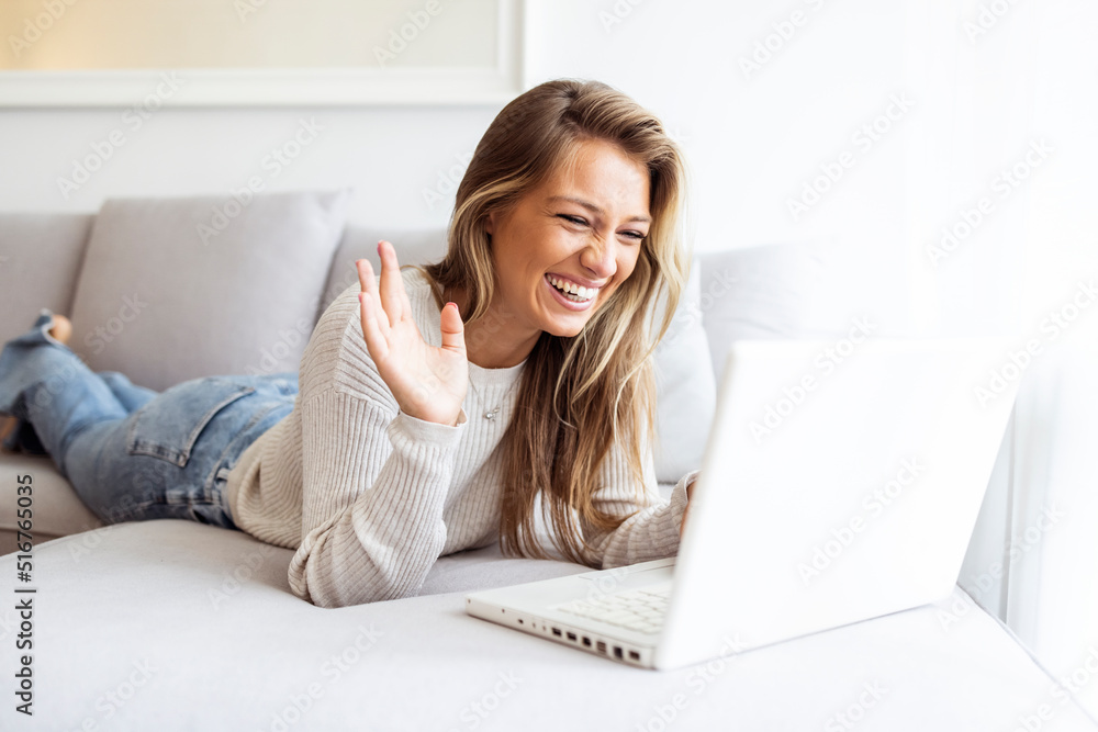 Young woman video calling using a laptop sitting on a sofa . Smiling young woman using laptop, sitting on couch at home. Beautiful girl shopping or chatting online in social network, having fun Young woman video calling using a laptop sitting on a sofa . Smiling young woman using laptop, sitting on couch at home. Beautiful girl shopping or chatting online in social network, having fun