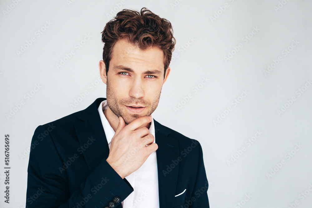 Closeup portrait of handsome confident stylish hipster lambersexual model. Sexy modern man dressed in black elegant suit. Fashion male posing in studio. Touching his chin Closeup portrait of handsome confident stylish hipster lambersexual model. Sexy modern man dressed in black elegant suit. Fashion male posing in studio. Touching his chin