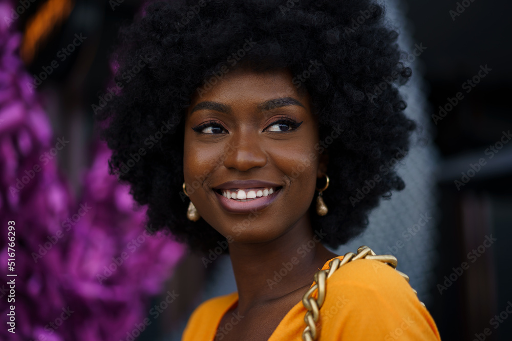 Photo of a stylish young black woman with curly hair wearing orange crop top walking in the street Photo of a stylish young black woman with curly hair wearing orange crop top walking in the street